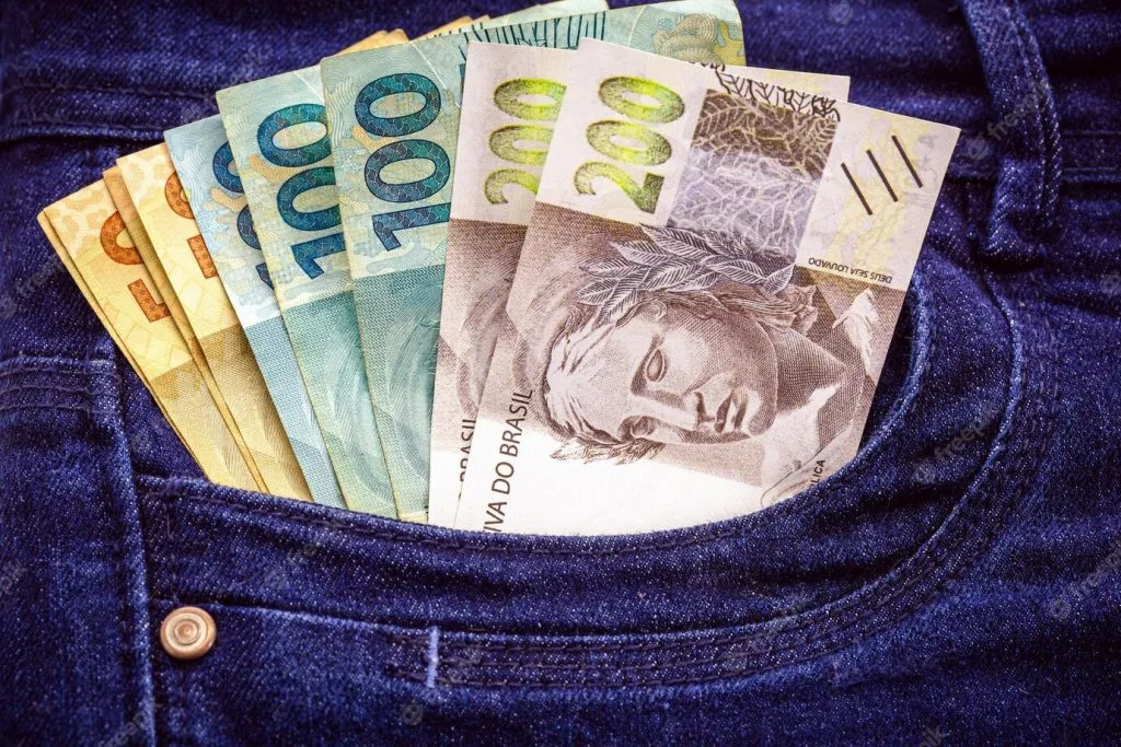 Cédulas de reais no bolso de uma calça jeans